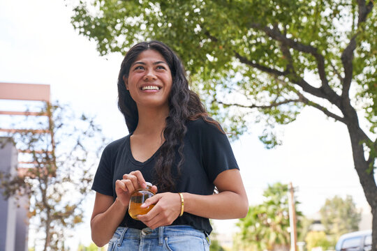 Woman drinks apple juice outdoors smiling