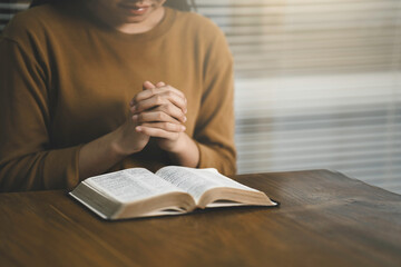 Pray worship and read the Bible God at the table in church on Sunday mornings. Christian women hold Hand prayer and confession at home - obrazy, fototapety, plakaty