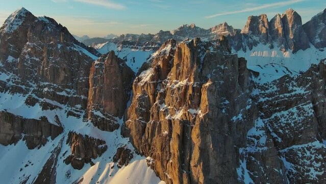 Aerial around view of amazing rocky mountains in snow at sunrise, Dolomites, Italy, 4k