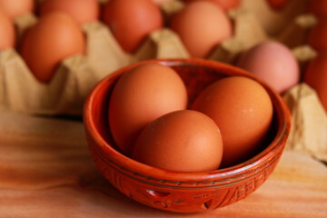Fresh eggs in a bowl on a wooden table. Selective focus.