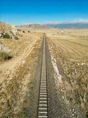 Fototapeta na wymiar Top view of the train track passing through the arid land, taken with a drone