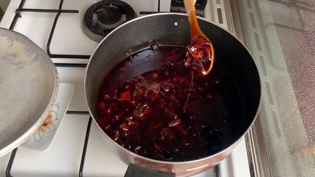 Slow food cooking at home red syrup for sweet quince jam stir and mix wild apple fruit slices to make delicious Persian cooking cuisine gourmet culinary dessert in a big city in Tehran urban life Iran