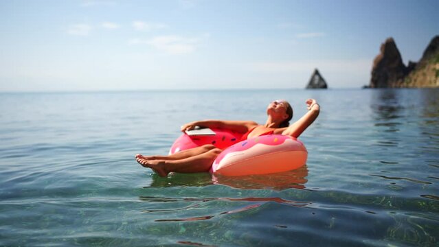 Summer vacation woman in hat floats on an inflatable donut mattress. Happy woman relaxing and enjoying family summer travel holidays travel on the sea.