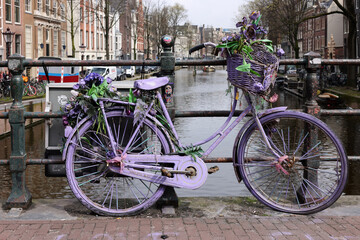 Fototapeta na wymiar Old lavender colored bicycle on the bridge in De Wallen - called the red light district. It is famous for its entertainment character
