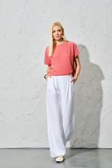 Smiling blonde woman in pink shirt and white trousers, spring portrait