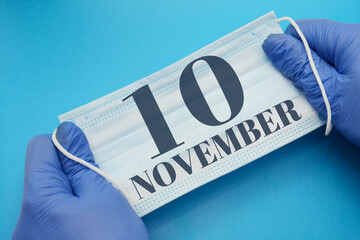 10 november day of month. Doctor holding an antivirus mask in blue medical gloves on blue...