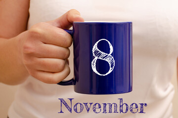The inscription on the blue cup 8 november. Cup in female hand, business concept