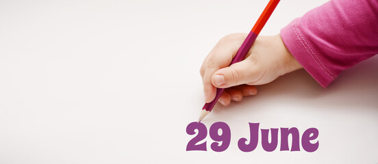 A child's hand writes 29 june in a lilac pencil. Banner with copy space