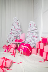 Gift boxes in pink lie under the Christmas tree on New Year's Eve
