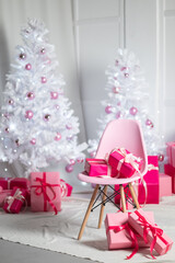 Gift boxes in pink lie under the Christmas tree on New Year's Eve