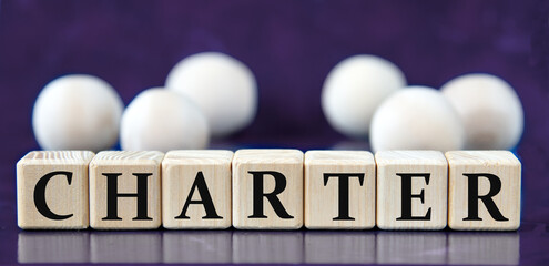 CHARTER - word on wooden cubes on a blue background with wooden balls