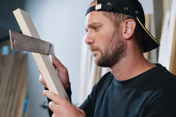 Portrait of a professional carpenter who measures the evenness of the board with a ruler before...