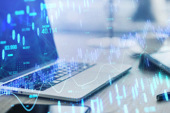 Close up of laptop on desk with objects and glowing candlestick forex chart on blurry background. Stock market, trading analysis and investment concept. Toned image. Double exposure.