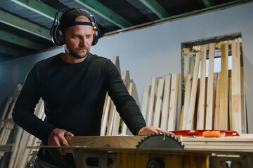 A carpenter uses an electric chopper to prepare boards for the manufacture of wood products.