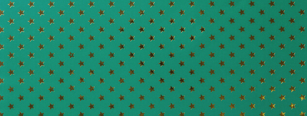 Dark green background from metal foil paper with a golden stars pattern.