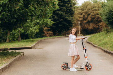 Cute young girl riding an electric scooter on sunny spring day. Electric urban transportation in Vilnius, Lithuania. Scooters for rent. Family leisure with kids.