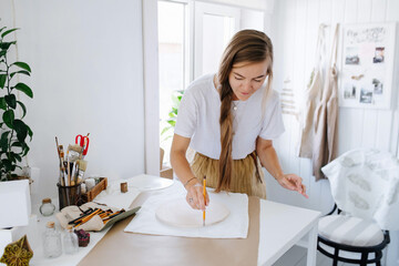 She is doing creative work, making a pencil sketch on fabric