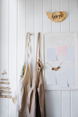 White wooden wall in a home workshop, hanging aprons and a board for notes
