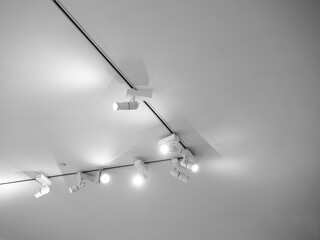 Gallery lighting, white LED picture light fixtures for art paintings or photography. Modern stainless steel track lights hanging on white ceiling background. - obrazy, fototapety, plakaty