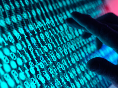 Hand of man touching screen displaying binary code