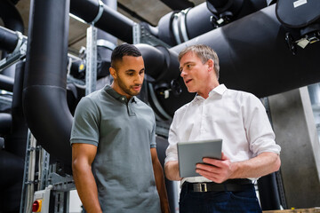 Employee and businessman with digital tablet talking in factory