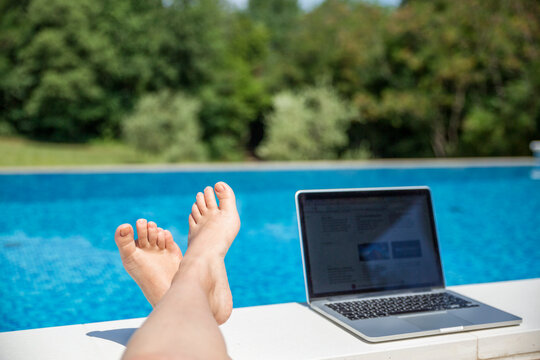 Foot of woman near laptop at poolside on sunny day