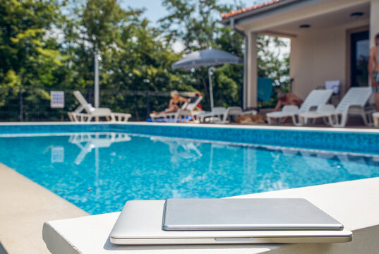 Laptop and tablet PC kept near swimming pool on sunny day - Powered by Adobe