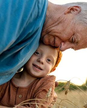 Loving grandfather embracing grandson near crop plants