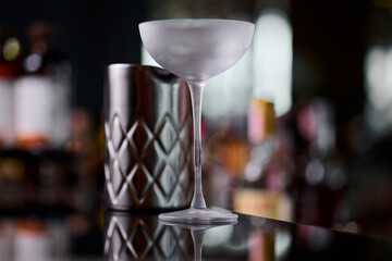 An empty frozen glass stands on the bar counter before preparing a cocktail. Restaurant bar counter