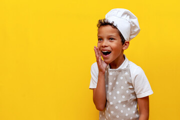 african american boy in uniform and chef's hat announces loudly and shouts on yellow isolated background - obrazy, fototapety, plakaty