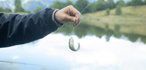 Man catching and showing small fish in the lake.