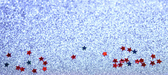 Red and blue stars of confetti on a blue cold blurred snowy background. Brilliant colored sequins....
