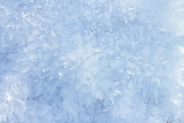 Background of snow crystals. Frozen river close-up. Blue winter Christmas background. Copy space. Beautiful snowflakes, crystals, close-up on ice. Template for postcards, calendars, covers