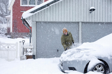Man cleaning snow off car in winter