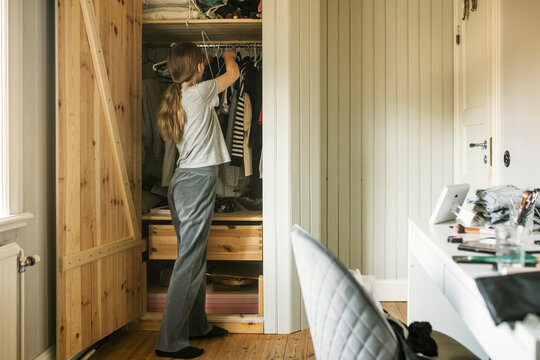Girl looking at clothes in her wardrobe