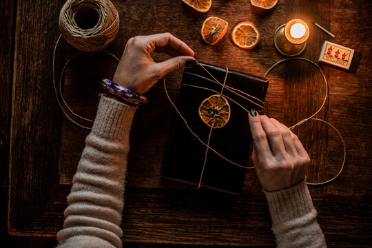 Hands of woman tying dried lemon slice to book
