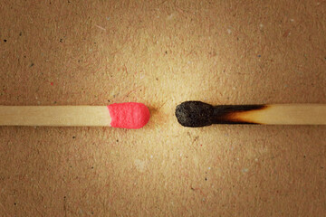 Close-up of unused matchstick in fornt of a burnt one on recycled paper background - Concept of...
