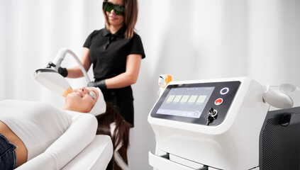Selective focus of diode laser device cosmetology equipment with cosmetologist and patient on...
