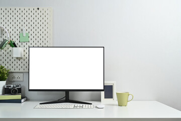 Front view computer monitor with blank screen, camera, books and houseplant on white table