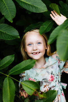 Smiling girl standing under branches of tree