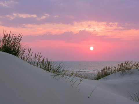 Sand dunes on beach during sunset
