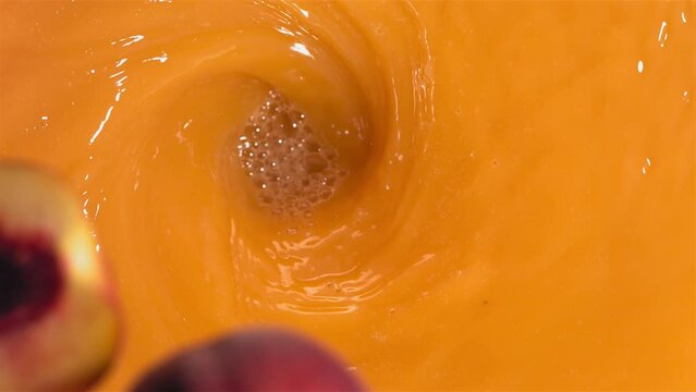 Super Slow Motion Shot of Fresh Peaches Falling into Juice Whirl