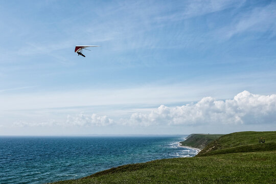 Man hang gliding over coast