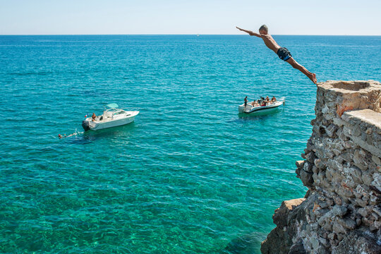 Boy diving into sea from cliff