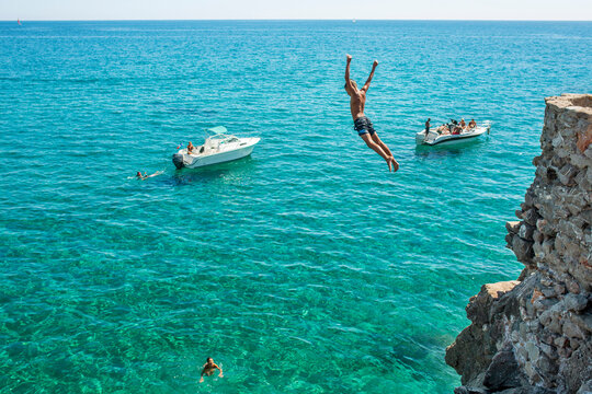 Boy diving into sea from cliff