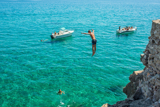 Boy diving into sea from cliff