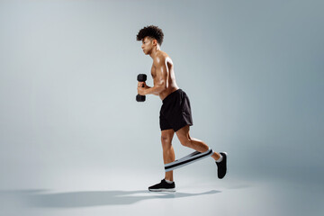 guy holding dumbbells exercising with loop band on legs, studio