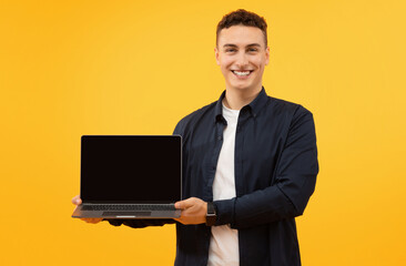 Happy young man holding laptop computer with black blank screen
