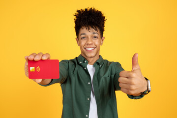 Happy african american guy showing bank credit card - obrazy, fototapety, plakaty
