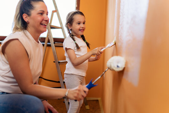 Mother and daughter are painting the girl's new room together